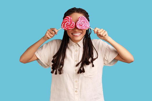 Romantic woman with black dreadlocks covering eyes with sugary hear shape candies.