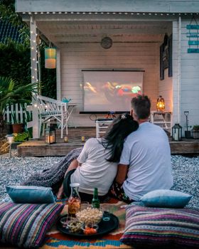 couple looking movie in garden at night , people looking movie in the garden, garden cinema night at home