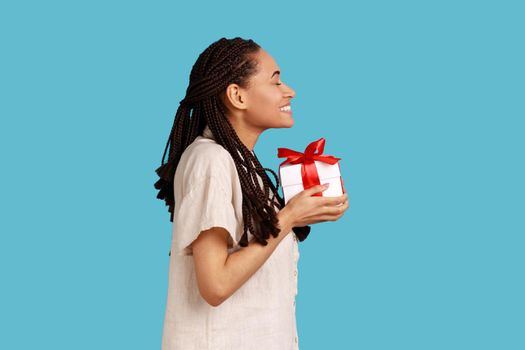 Woman with black dreadlocks holding present box, congratulating, extremely happy to get gift.