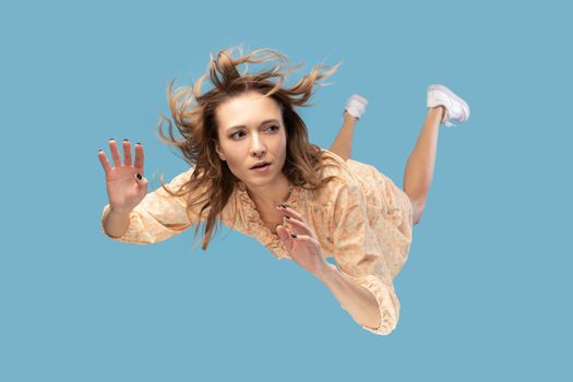 Beautiful young woman levitating in mid-air, falling down and her hair messed up soaring from wind