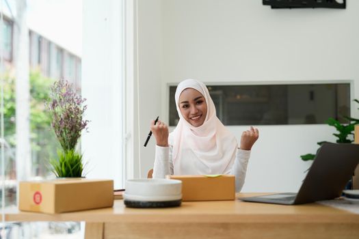 excited asian muslim woman small business owner look at camera