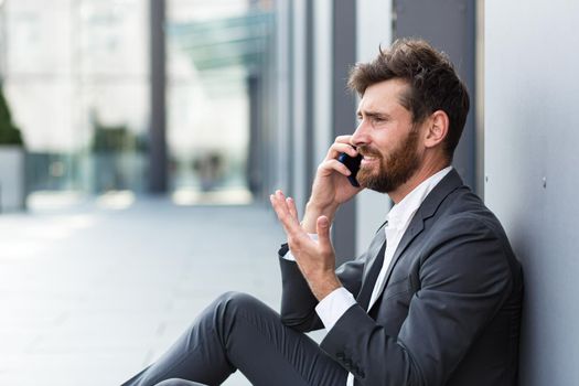 Businessman in despair reports bad news talking on the phone, depressed and sad