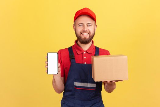 Deliveryman holding cardboard box with ordered online goods, showing cell phone with empty screen.