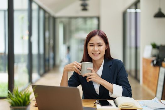 Asian businesswoman taking a coffee break while using a computer