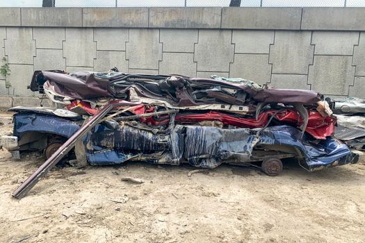 A pile of compressed cars going to be shredded, crushed junk vehicles on scrapyard.