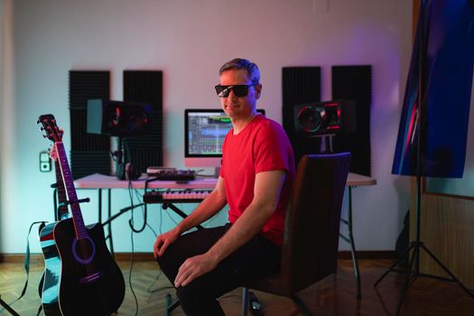 Music producer poses with sunglasses at his home studio