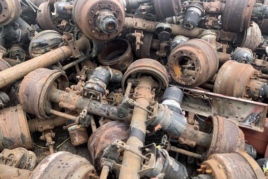 Pile of old rusty truck axle for reusing, used automotive part for sale, old rear differential of truck, car rear axle on junk yard.