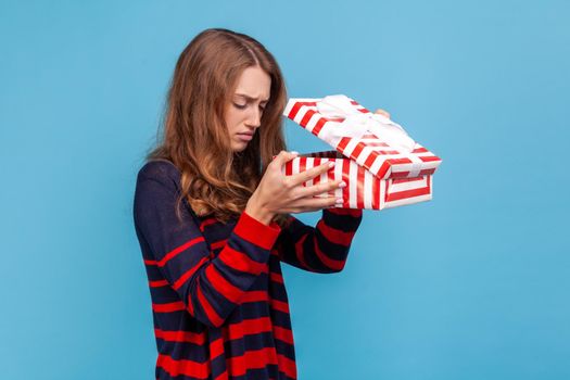 Woman looking inside present box and expressing sadness, hoped to get another gift.