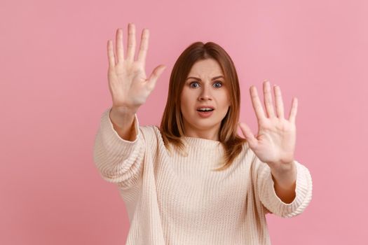 Blond woman gesturing stop with palms and looking surprised with frightened eyes.