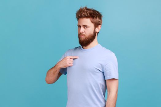 Man in blue T-shirt standing pointing himself, feeling self-important, proud, famous