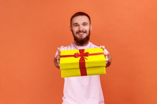Man giving gift box to camera with excited smile, greeting on holiday and sharing present.
