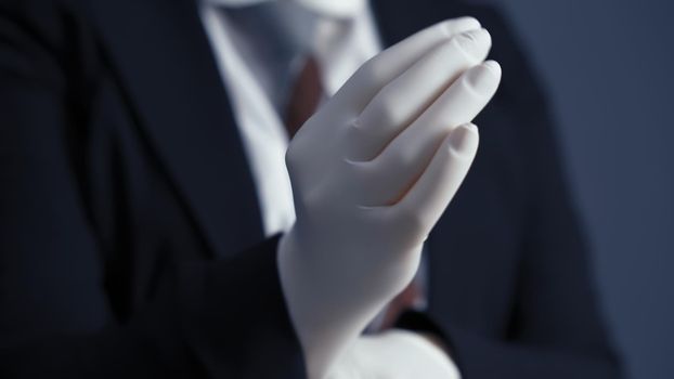 Business person puts on white disposable gloves. Business during and after quarantine. Close up shot
