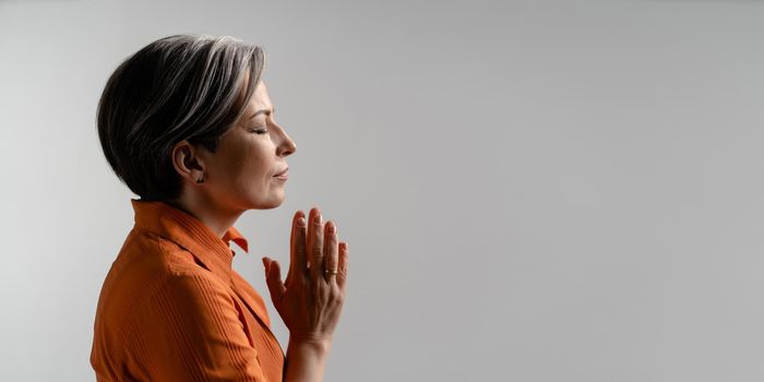 Mature woman folded hands for prayer. Spiritual Caucasian woman closed eyes. meditation concept. Profile view. Horizontal template for ad banner with copy spase for text at right