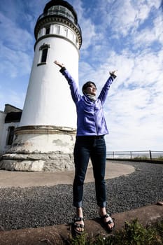 Woman's joyful expression by a lighthouse.