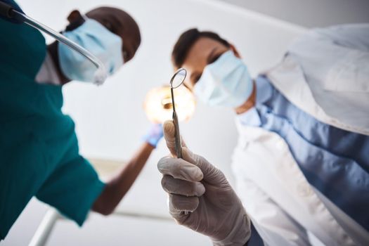 Here comes the dental squad to save the day. Low angle shot of two dentists getting ready to perform a procedure on a patient.