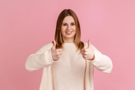 Blond woman looking at camera with toothy smile and showing thumbs up, approval sign, good feedback,