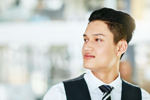 Young professional waiter, bartender or host looking confident, serious and wearing formal uniform on a blurred background. Closeup side profile, head and face of a man working in hospitality
