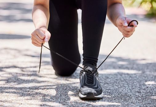 Lace up, lets burn some calories. a woman tying her shoelaces before going for a run outdoors.