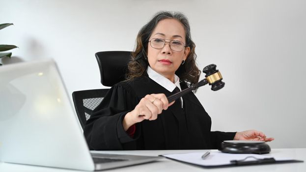 Mature judge or attorney in robe gown uniform consulting online via video conferencing on laptop computer