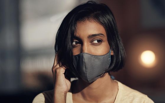 To wear or not to wear Is that even a question. a young woman wearing a face mask and looking thoughtful.