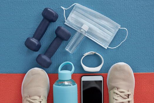 Commit to be fit. Studio shot of a variety of workout equipment and PPE on a red and blue yoga mat.