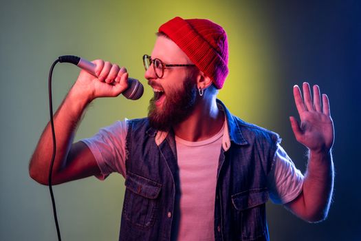 Man with beard singing songs at karaoke holding microphone, singer making performance, entertainment
