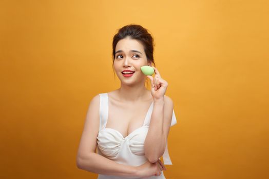 Closeup portrait of young beautiful woman is holding beauty blender for applying makeup foundation sponge