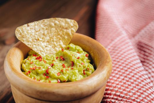 guacamole bowl with nachos on a wooden table