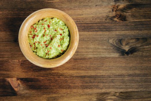 bowl of mexican guacamole on a wooden table