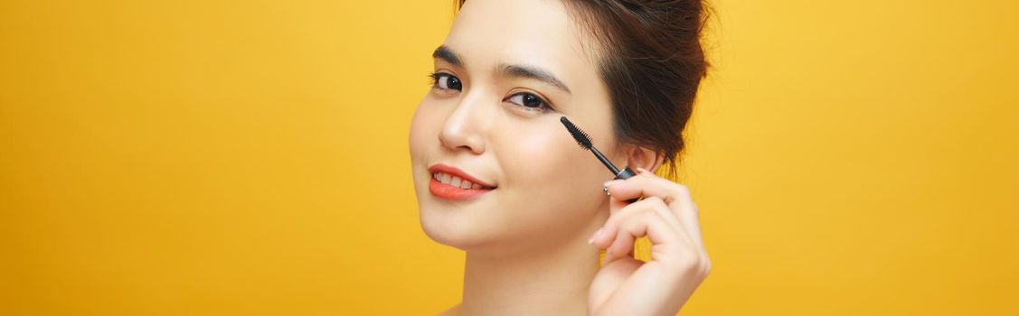 Women who make up makeup, eyelashes, mascara on yellow background