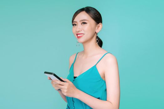 Attractive woman using text messaging feature on her portable device in studio