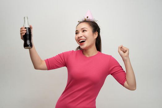 Stylish asian woman drinking soda dancing over white background