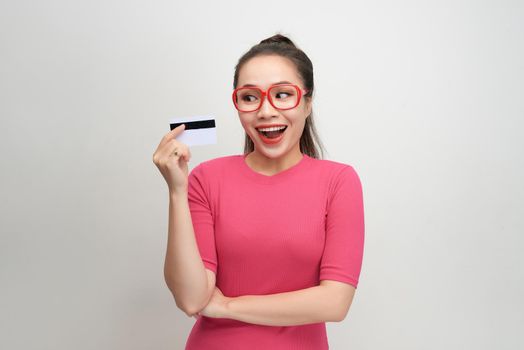 Photo of pretty young woman isolated over white background. Looking camera winking holding credit card.