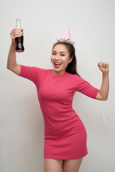 Stylish asian woman drinking soda dancing over white background