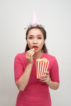 Portrait of an astonished woman holding popcorn isolated over white background