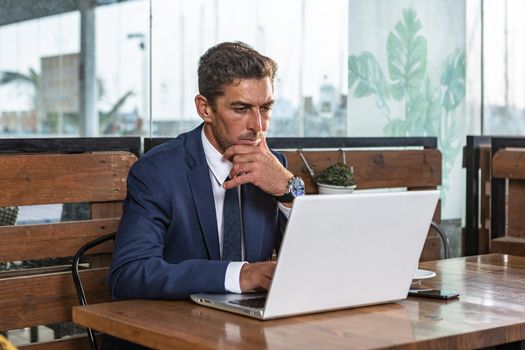 Thoughtful businessman analyzing data on laptop
