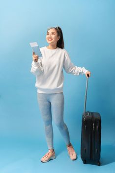 Tourism, summer holidays and vacation concept - Happy woman in casual clothing with travel bag and air ticket over blue background