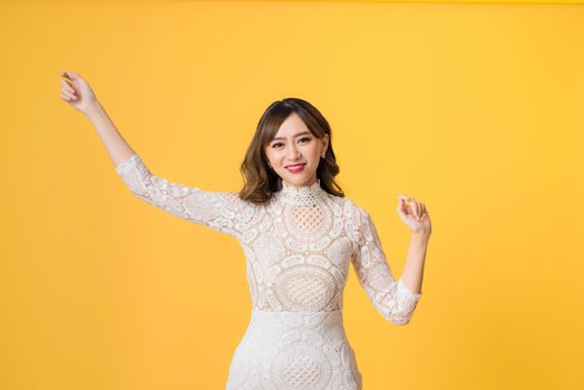 Young pretty Asian woman smiling with energetic movement studio shot isolatede on colorful yellow background
