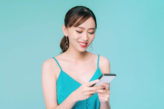 Attractive woman using text messaging feature on her portable device in studio