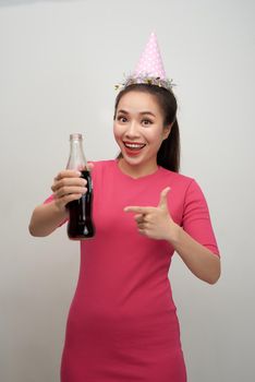 Drinks and people concept - happy young asian woman drinking soda from glass bottle over white background