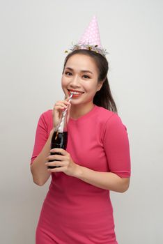 Portrait of beautiful crazy smiling woman on white drinking soda from bottle with straw