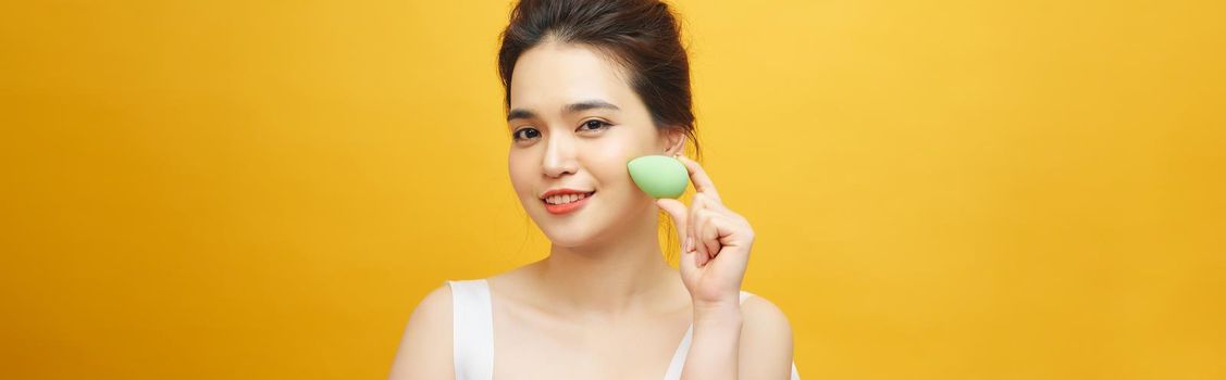 Closeup portrait of young beautiful woman is holding beauty blender for applying makeup foundation sponge