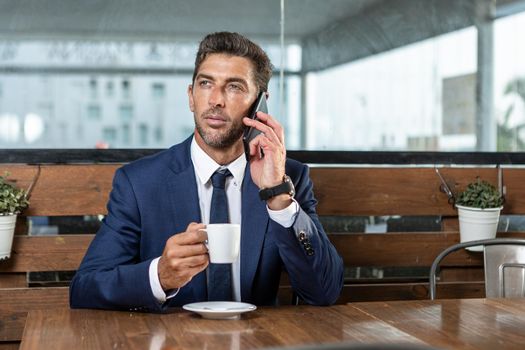 Businessman speaking on smartphone in cafe
