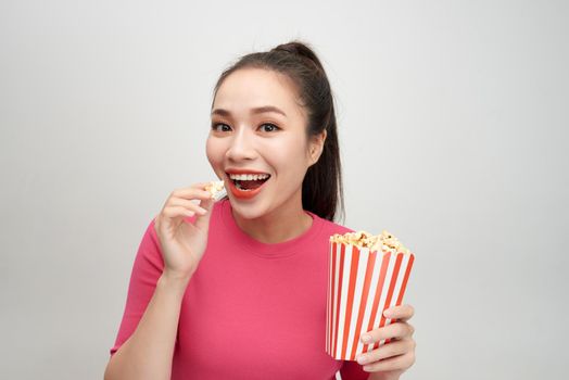 Portrait of a cheery pretty girl eating popcorn isolated over white background