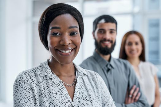Go-getters succeed in their own league. Portrait of a businesswoman standing in an office with her colleagues in the background.