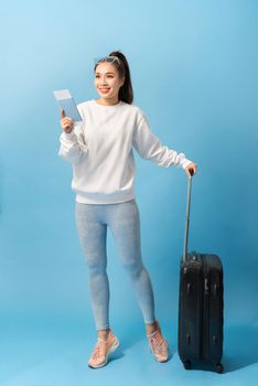 Tourism, summer holidays and vacation concept - Happy woman in casual clothing with travel bag and air ticket over blue background