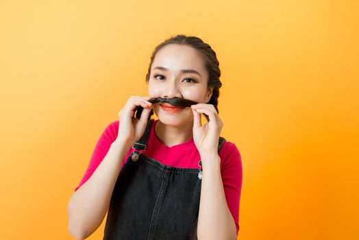 Photo portrait of young girl making fake mustache playful cool isolated on vivid yellow colored background