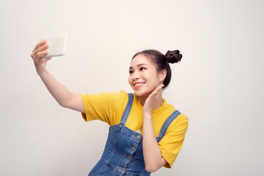 Young Asian woman wearing a jeans dungaree who taking selfie and smiling