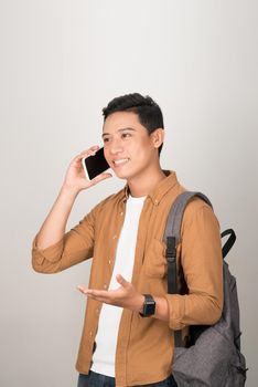 A handsome Asian student taking on cell phone isolated on white background