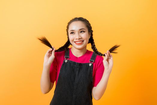 Cute mischievous young asian woman pulling her pigtails